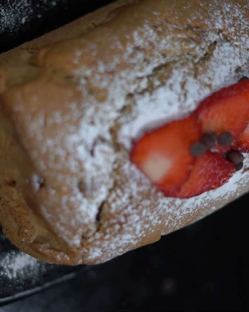 Torta de vainilla espolvoreada con azúcar, decorada con fresas.
