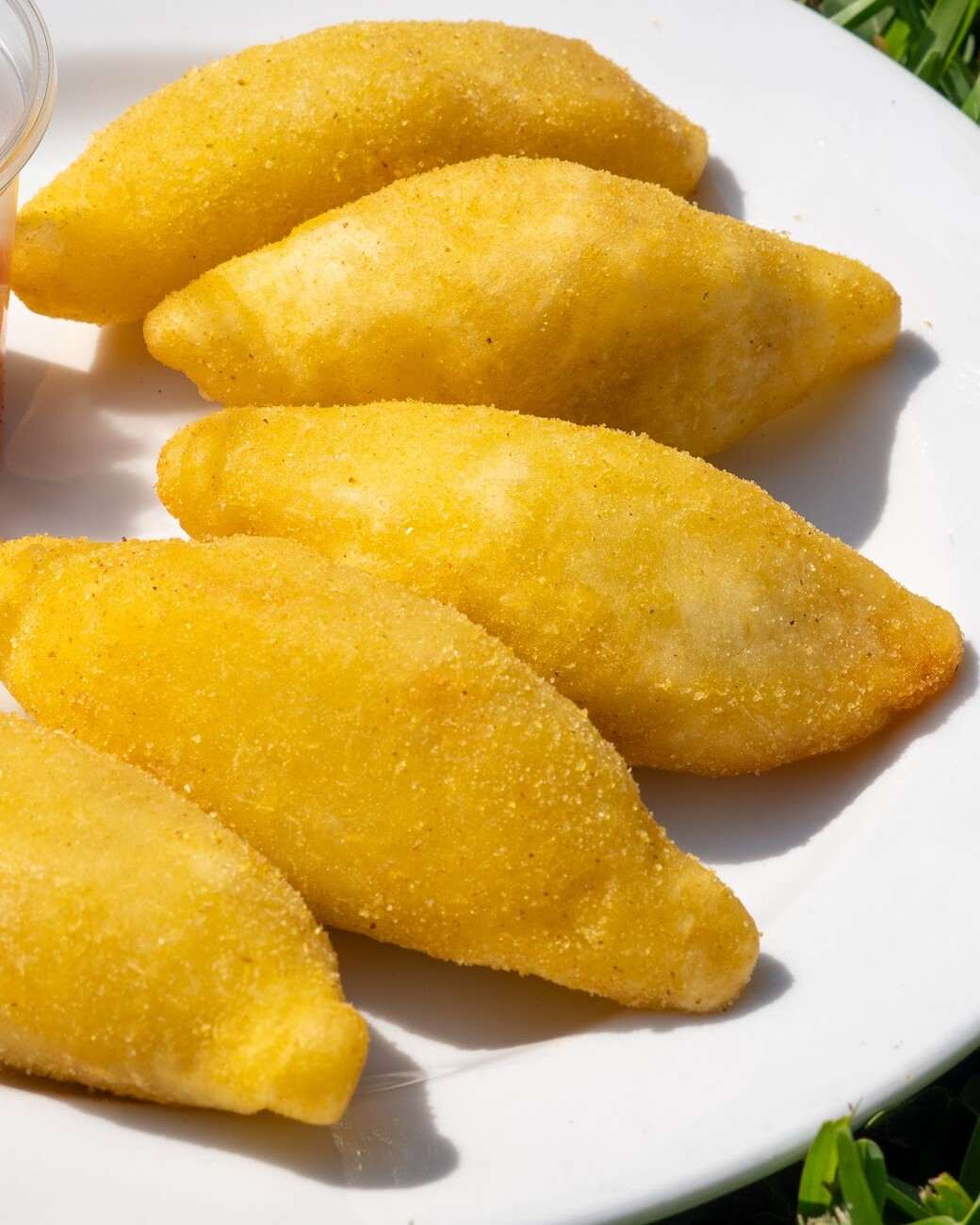 De cerca: empanadas de masa de maíz, doradas y crocantes, sobre un plato blanco.