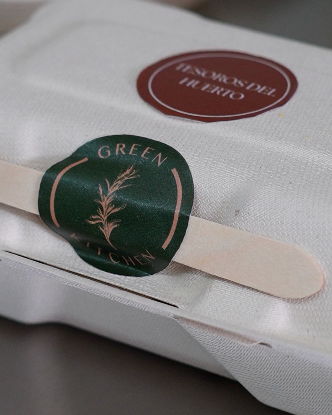 Envase biodegradable sellado con la etiqueta del plato, Tesoros del Huerto, el sello de Romero Green Kitchen y una cuchara de madera.
